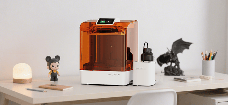 3D printer on a desk with various items including a figurine and a lamp.